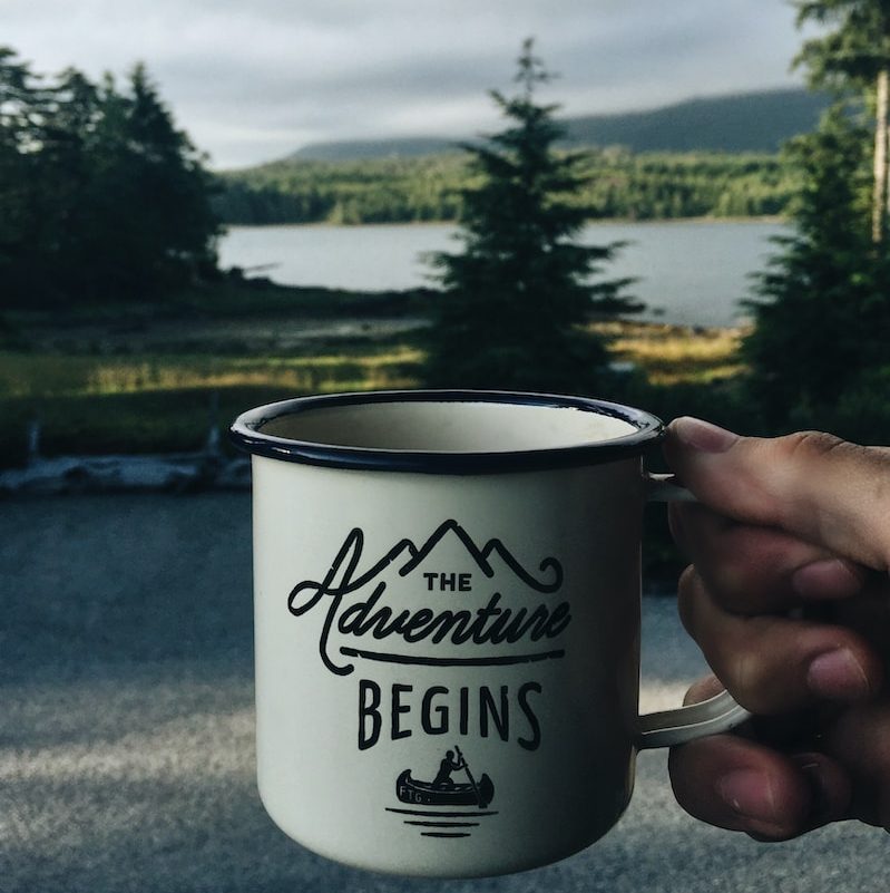 person holding cup with body of water background